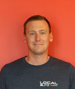 Man wearing Local Blitz shirt, red background.